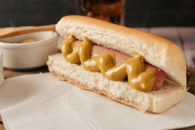 Close-up van een hotdog met mosterd op een wit papieren servet. Fastfood-concept.