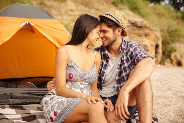 Close up van een jong gelukkig mooi paar zittend bij de tent op het strand en zoenen