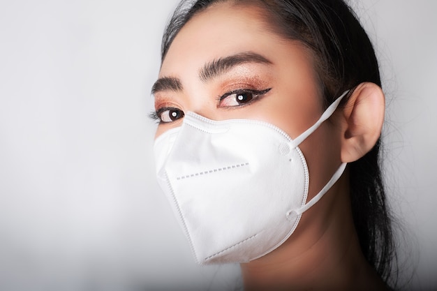 Close-up van een jonge Aziatische vrouw die een medisch masker opzet n95