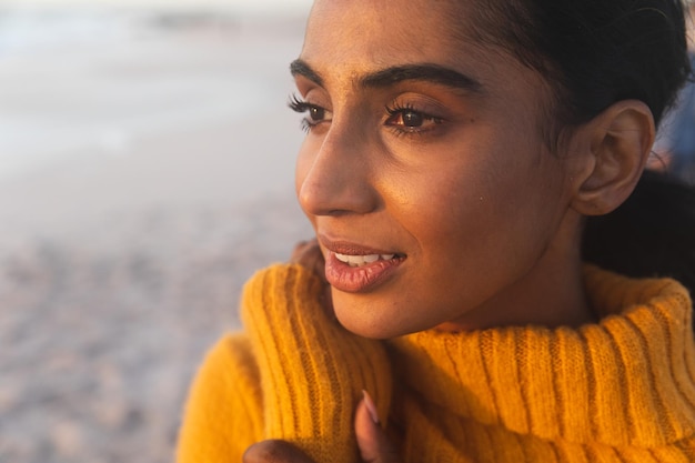 Close-up van een jonge biraciale vrouw die denkt terwijl ze naar het strand kijkt tijdens zonsondergang