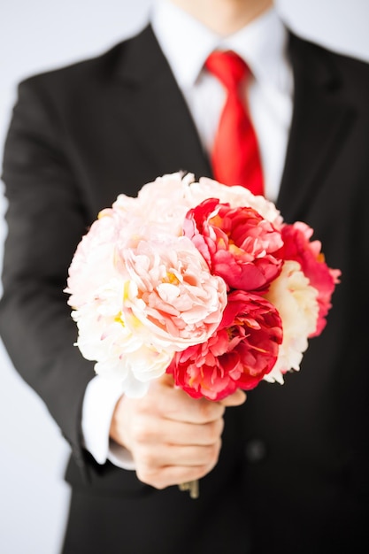 close-up van een jonge man die een boeket bloemen geeft