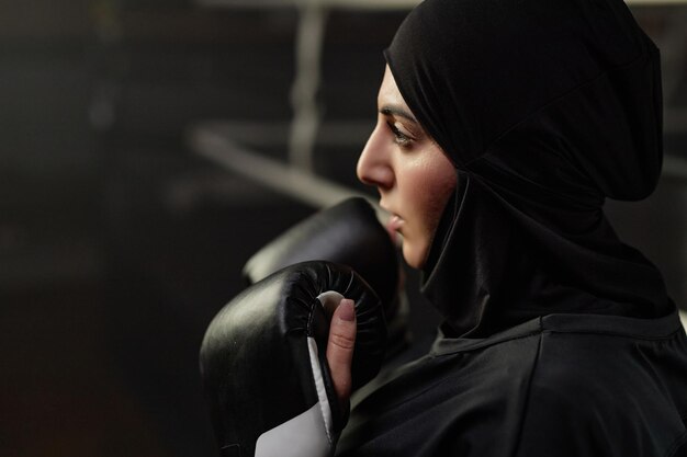 Foto close-up van een jonge sportvrouw in zwarte hijab en bokshandschoenen