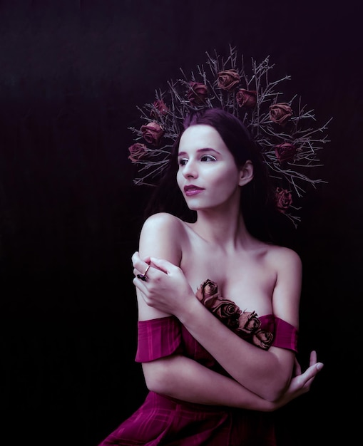 Close-up van een jonge vrouw die bloemen op haar hoofd draagt terwijl ze tegen een zwarte achtergrond staat