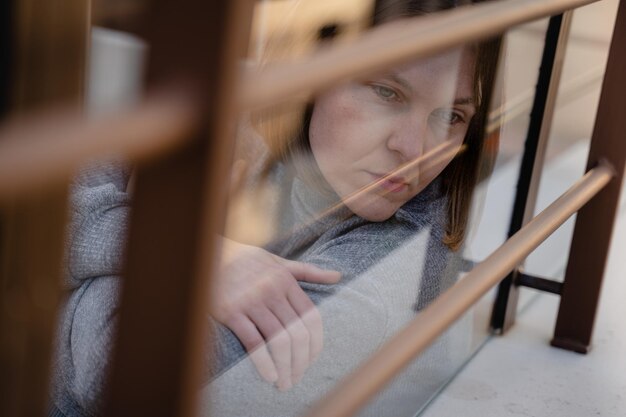 Foto close-up van een jonge vrouw die door het raam kijkt