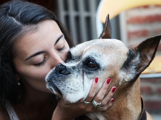 Close-up van een jonge vrouw die een hond zoent.