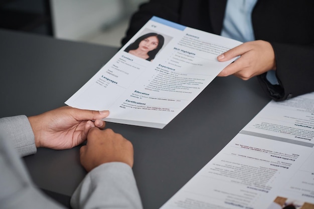 Foto close-up van een jonge vrouw die haar documenten geeft om een visum te krijgen terwijl ze op een vergadering zit