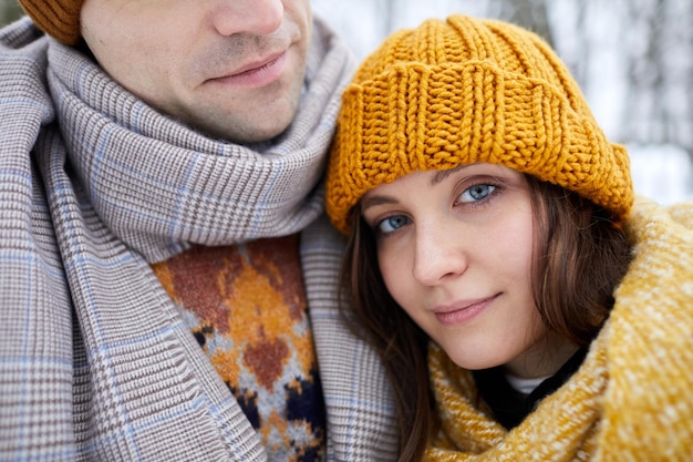 Close-up van een jonge vrouw die met haar hoofd op de schouder van de partner rust en glimlacht terwijl ze geniet van de wintervakantie