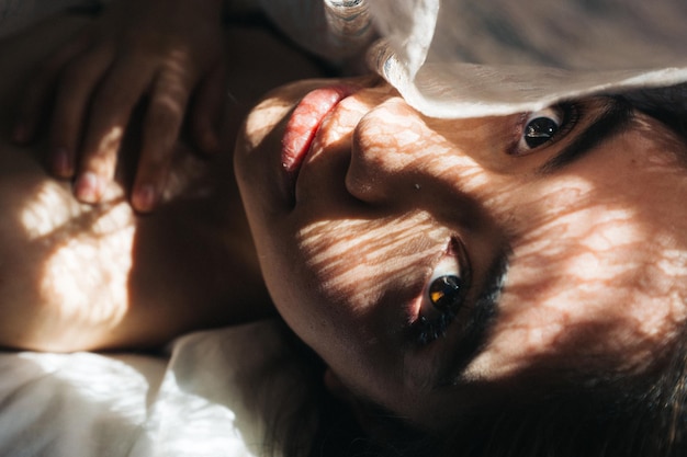 Close-up van een jonge vrouw die op bed ligt.