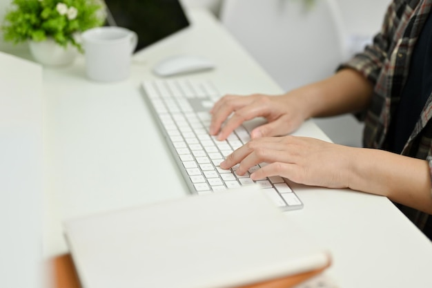 Close-up van een jonge vrouw die op het toetsenbord typt terwijl ze in haar kantoor werkt