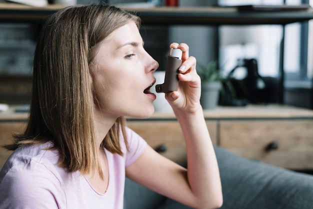 Close-up van een jonge vrouw met behulp van astma-inhalator