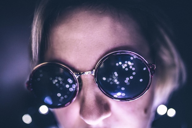 Foto close-up van een jonge vrouw met een zonnebril in een verlichte kamer