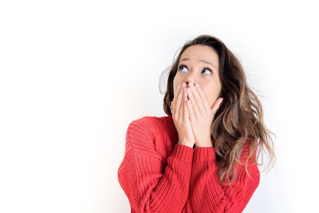 Close-up van een jonge vrouw met handen die haar mond bedekken tegen een witte achtergrond
