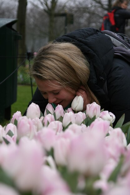 Close-up van een jonge vrouw met roze bloemen in het park