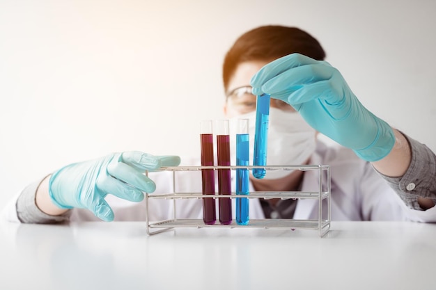 Foto close-up van een jonge wetenschapper die vloeistof in een reageerbuis in het laboratorium vasthoudt