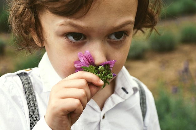 Close-up van een jongen die bloemen ruikt