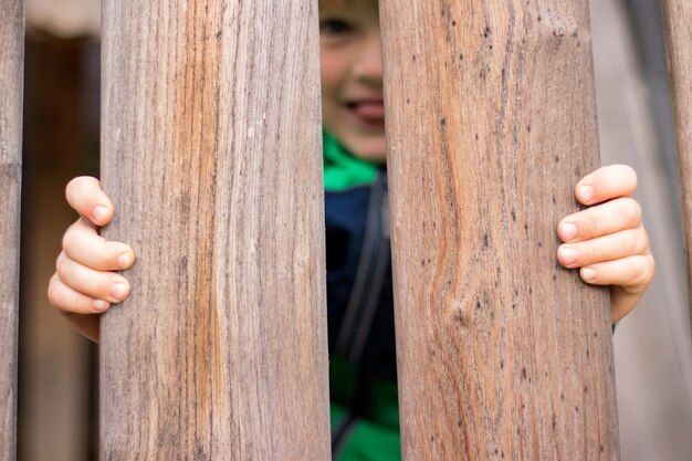 Foto close-up van een jongen die een houten reling vasthoudt