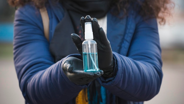 Foto close-up van een jongere die antiseptische of antibacteriële spray in de hand houdt