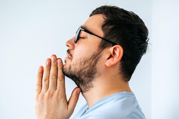 Close-up van een kalme spirituele knappe Amerikaanse man met een glasloze biddend met gesloten ogen zijaanzicht o