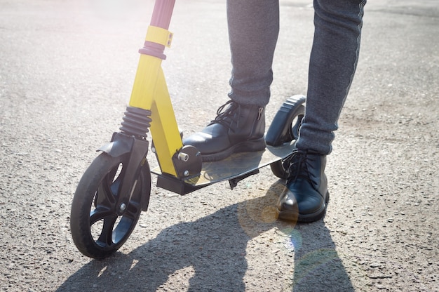 Close-up van een kind dat op het punt staat op een scooter te rijden. Benen van meisje op scooter op de weg.