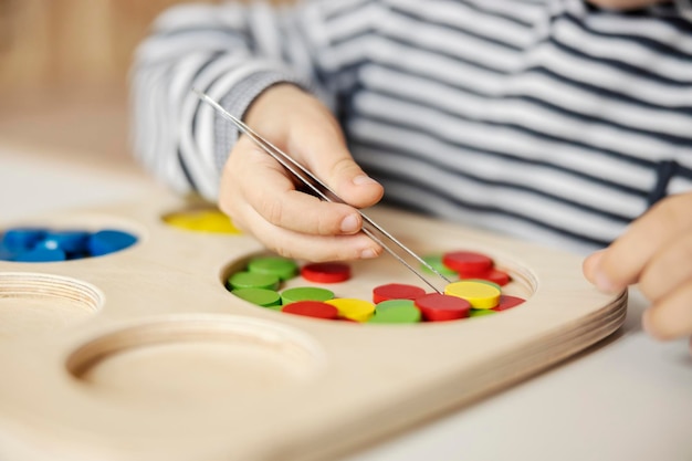 Close-up van een kleine jongen die motorische vaardigheden en kleuren leert door met montessori-speelgoed te spelen