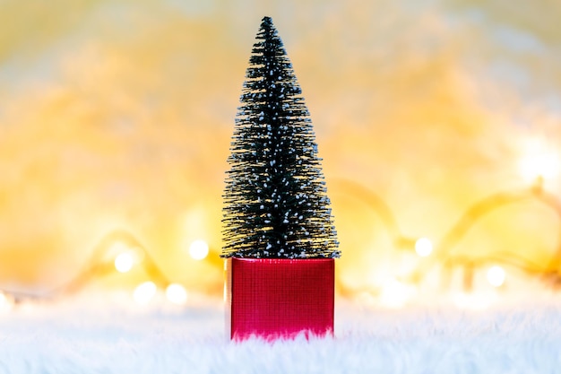 Foto close-up van een kleine kerstboom op een geschenk tegen verlichte strijklichten