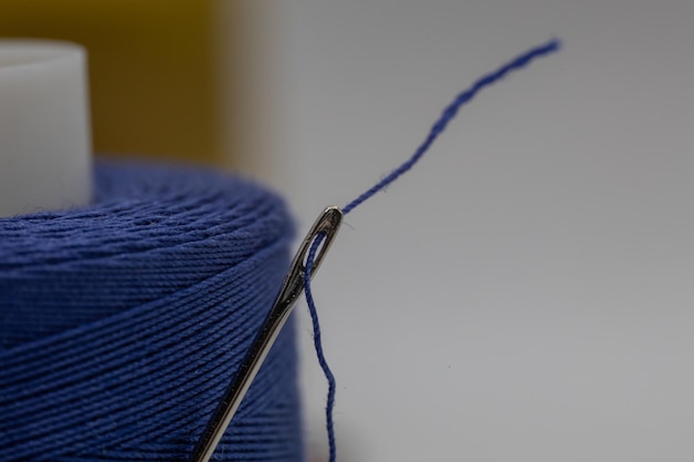Close-up van een kleine naald in een blauwe draad op de onscherpe achtergrond