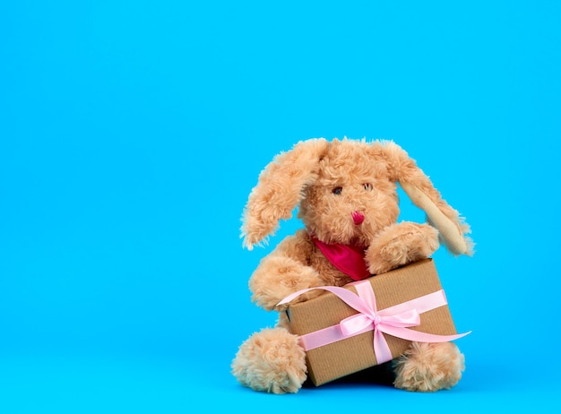 Foto close-up van een knuffeltje met een geschenk op een blauwe achtergrond