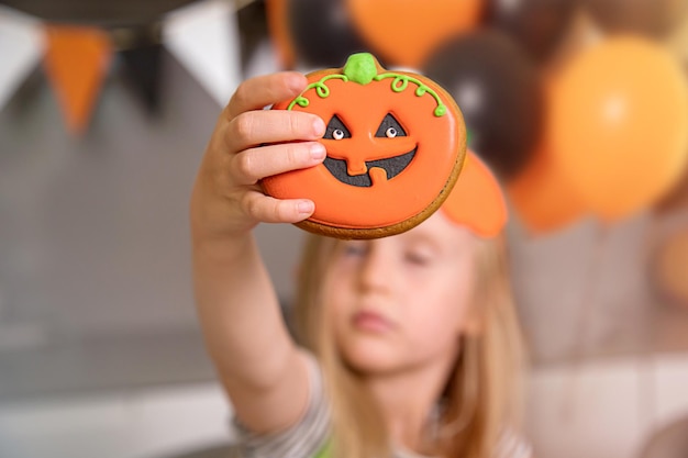 Close-up van een koekje dat eruitziet als een pompoen in de hand van een klein meisje