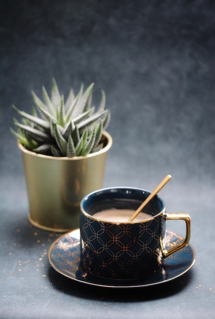 Close-up van een koffiekop met een potplant op tafel