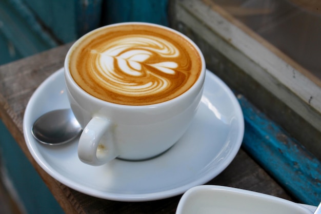 Close-up van een koffiekop met schuimkunst op een houten tafel