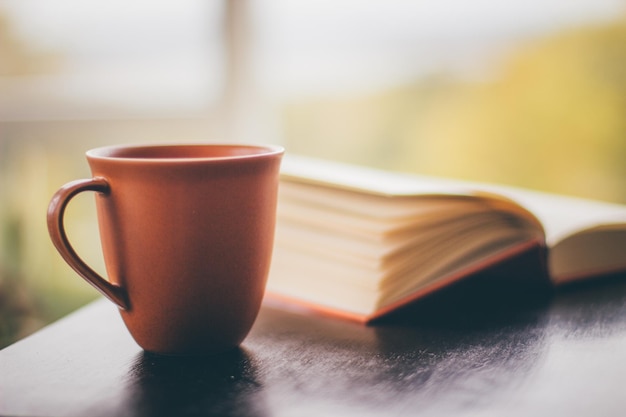 Close-up van een koffiekop op tafel naast een boek