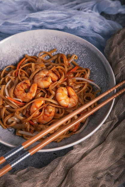 Foto close up van een kom chinese noedels met garnalen en eetstokjes chinese keuken