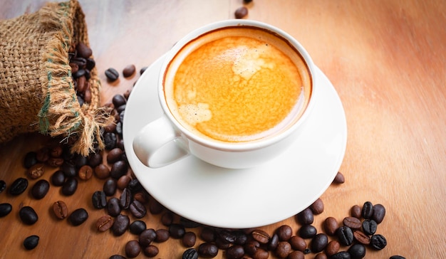 Close-up van een kopje latte met gouden schuim en gemengde of blend koffiebonen in een bruine zak