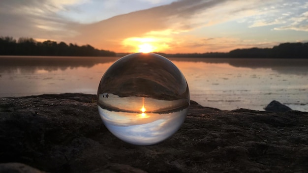 Foto close-up van een kristallen bol op een rots tegen de hemel bij zonsondergang