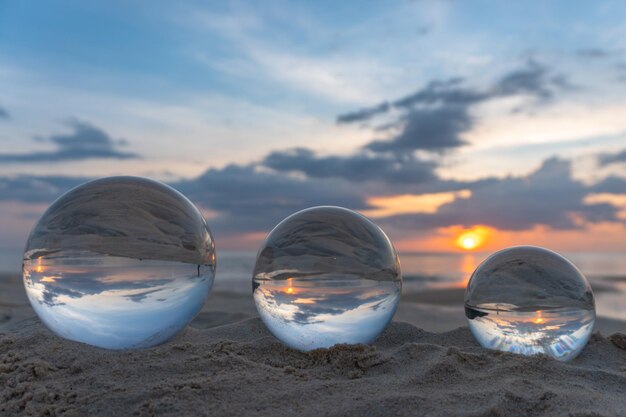 Foto close-up van een kristallen bol op het strand tegen de hemel bij zonsondergang