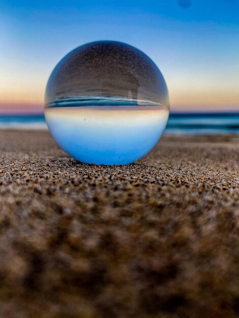 Foto close-up van een kristallen bol op het zand