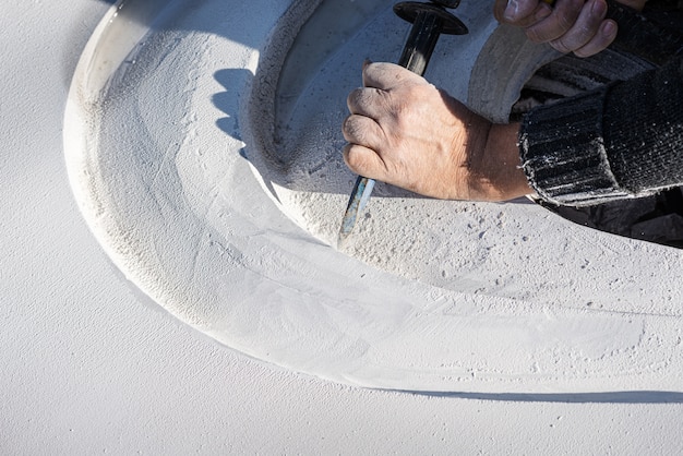 Close-up van een kunstenaar die bochten in een witte steen snijdt met nauwkeurige gebaren met behulp van een beitel