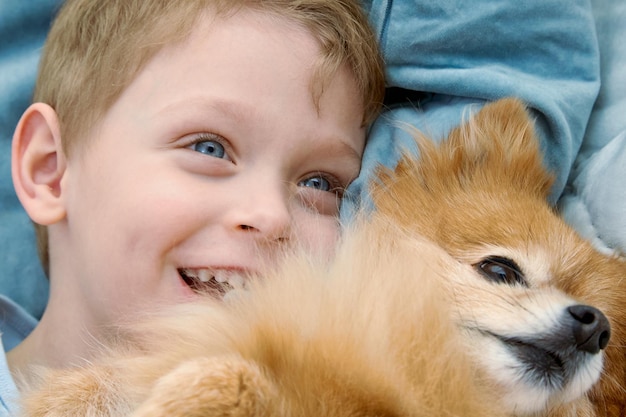 Close-up van een lachend blond kind dat zachtjes een schattige rode hond knuffelt