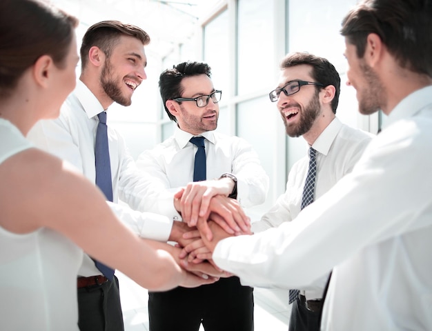 Close-up van een lachend business team staat met hun handen in elkaar gevouwen