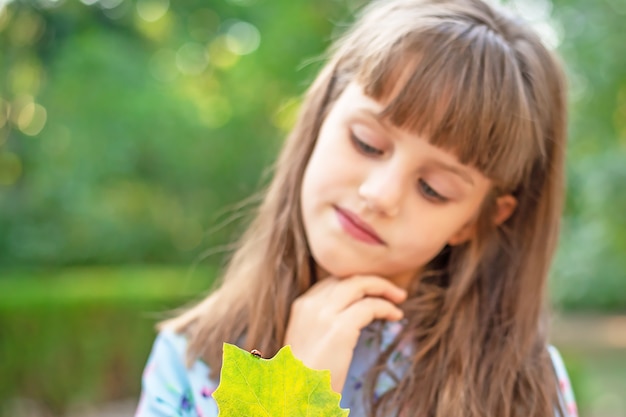 Foto close-up van een lieveheersbeestje op een boomblad in de hand van een klein schattig meisje. selectieve aandacht van de afbeelding.