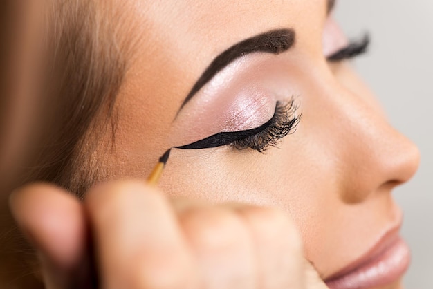 Close up van een make-up man artiest die eyeliner krijgt om te modelleren.