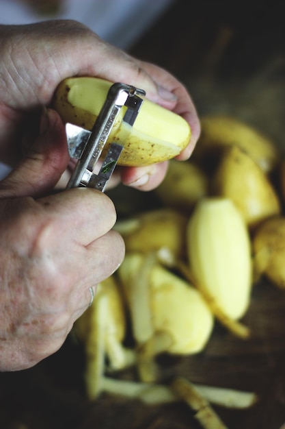 Close-up van een man die aardappelen schilt
