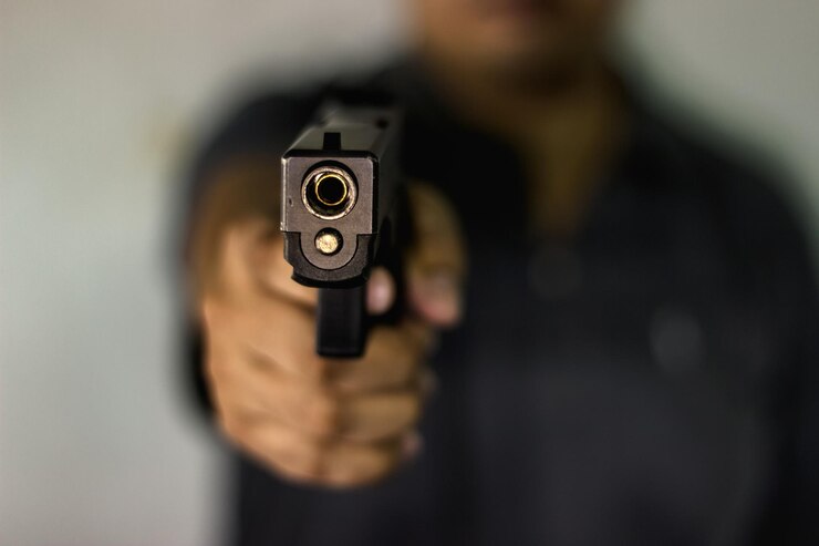 Foto close-up van een man die een pistool richt tegen een wazige achtergrond