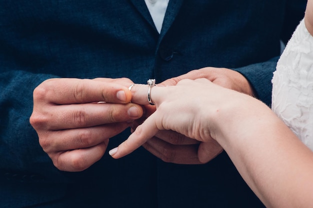 Close-up van een man die een ring aan de hand van de bruid legt