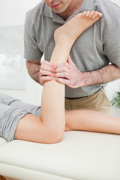 Close-up van een man die het been van een vrouw masseert