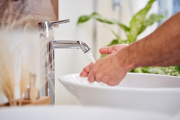 Close-up van een man die 's ochtends zijn handen in de badkamer wast