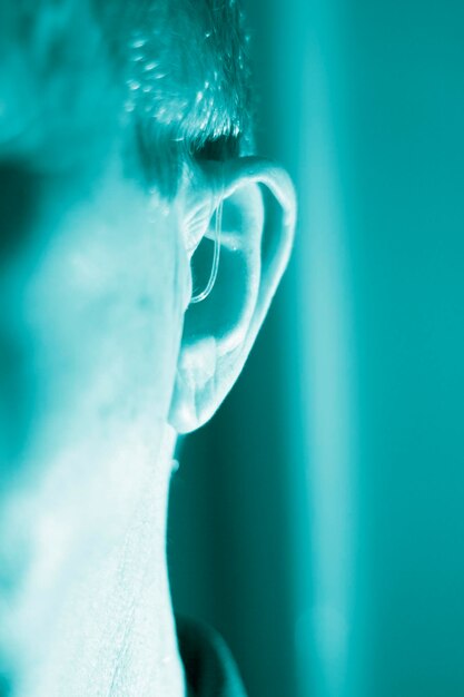 Foto close-up van een man die thuis een gehoorapparaat draagt