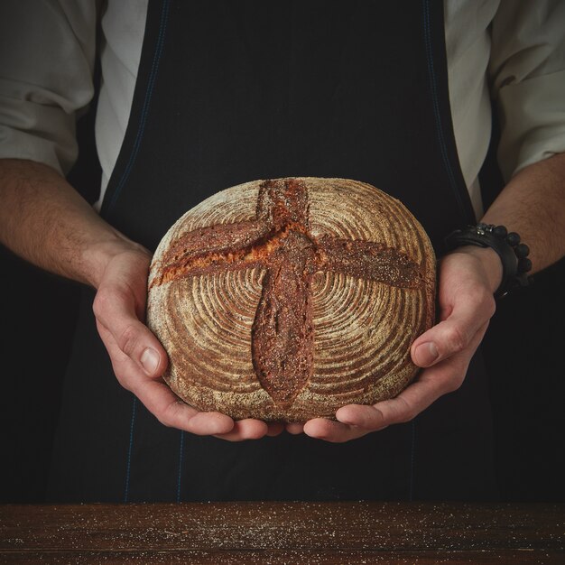 Close-up van een man hand met een rond donker brood