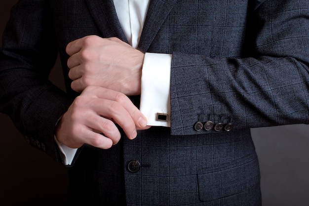 Close-up van een man in een smoking die zijn manchetknoop bevestigt