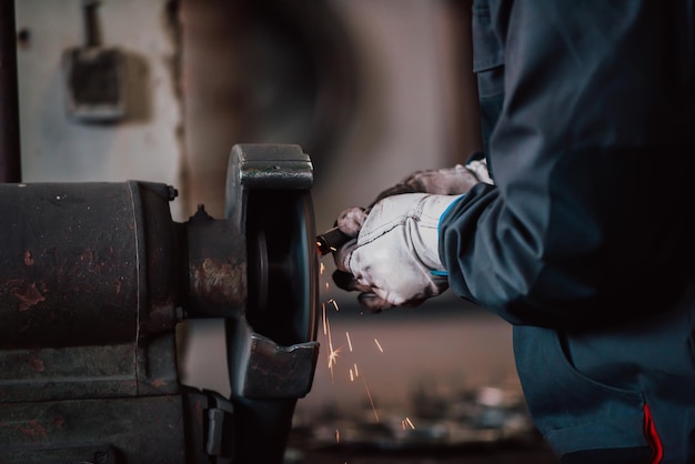 Close-up van een man in handschoenen die ijzermaterialen polijst in een industrie